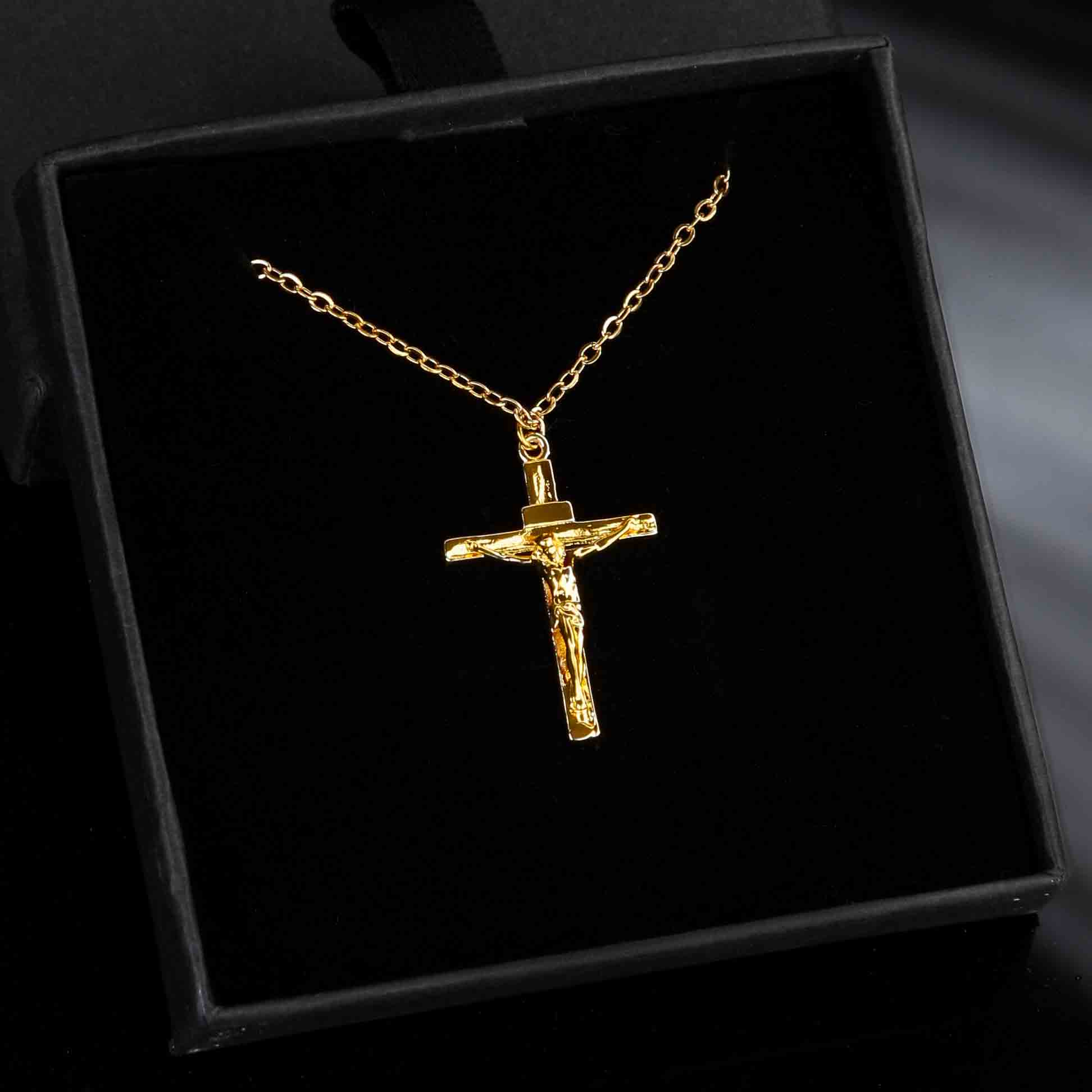 Collier croix Jésus en acier inoxydable doré avec pendentif crucifix détaillé, présenté dans un écrin noir élégant.
