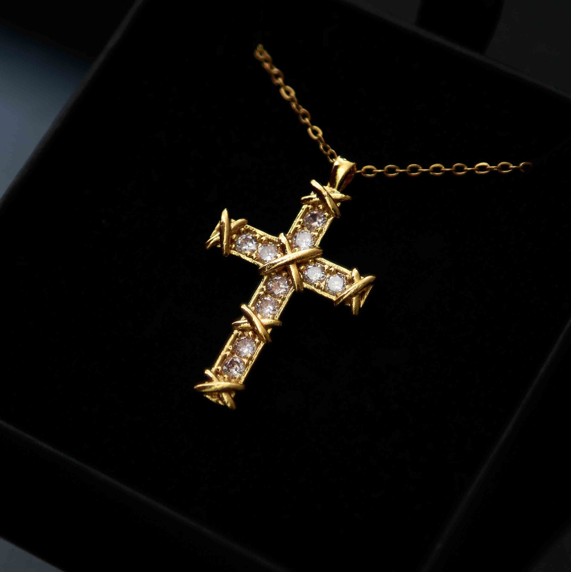Collier croix doré avec incrustations de pierres brillantes et détails en relief, parfait pour une touche élégante et spirituelle.