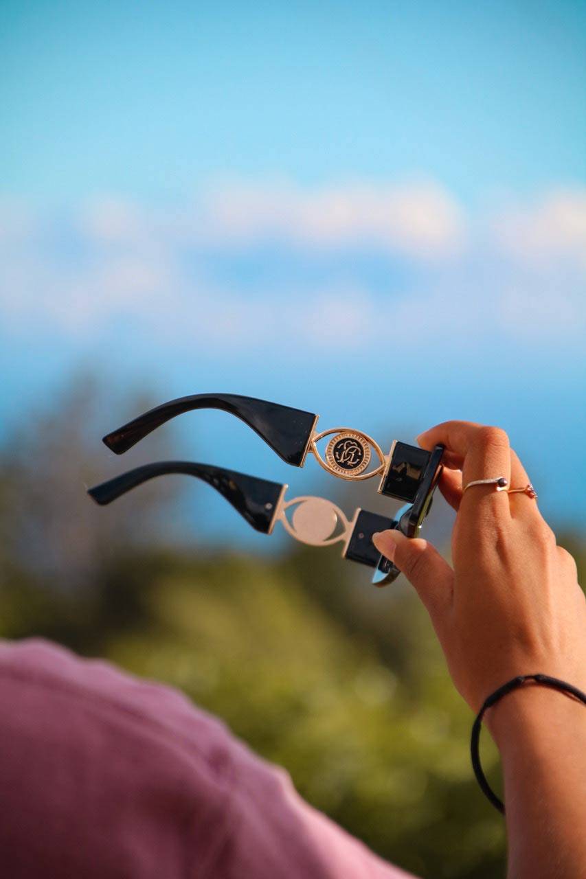 Lunettes monture carrée noires tenues à la main en extérieur, mettant en valeur leur design luxueux et leur confort pour homme.